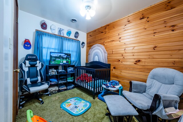 carpeted bedroom featuring wood walls and a crib