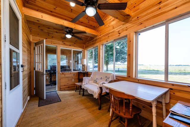 sunroom with vaulted ceiling with beams, wooden ceiling, plenty of natural light, and ceiling fan