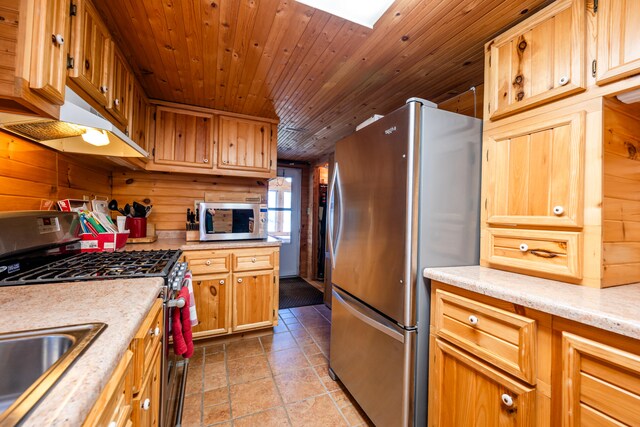 kitchen featuring stainless steel appliances, wooden ceiling, a skylight, and wooden walls