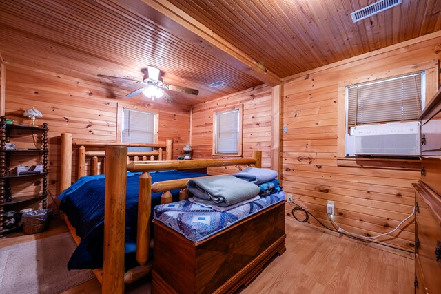 bedroom with wood walls, light hardwood / wood-style flooring, cooling unit, wooden ceiling, and ceiling fan