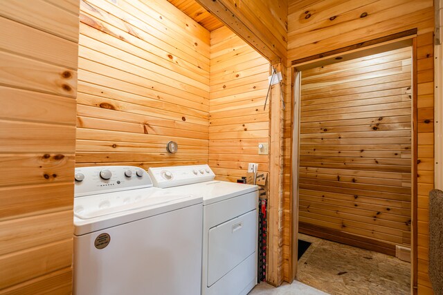 laundry area with wooden walls and washing machine and clothes dryer