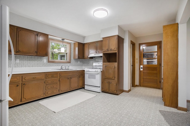 kitchen featuring under cabinet range hood, white appliances, tasteful backsplash, and a sink