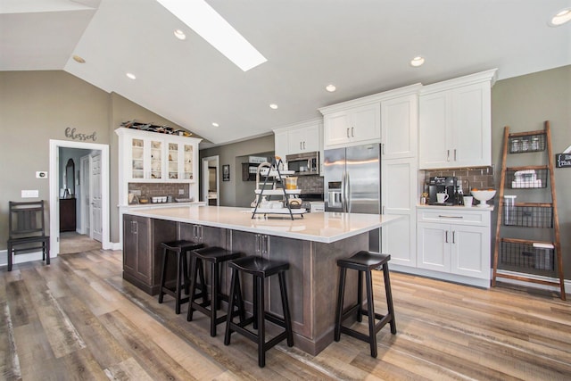 kitchen featuring appliances with stainless steel finishes, tasteful backsplash, a large island with sink, and white cabinetry