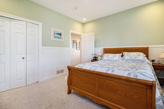 bedroom featuring light colored carpet, ceiling fan, and a closet