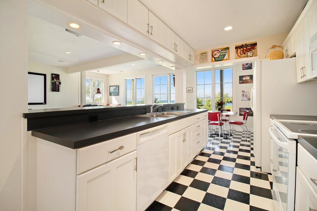 kitchen featuring white appliances, white cabinetry, and a healthy amount of sunlight