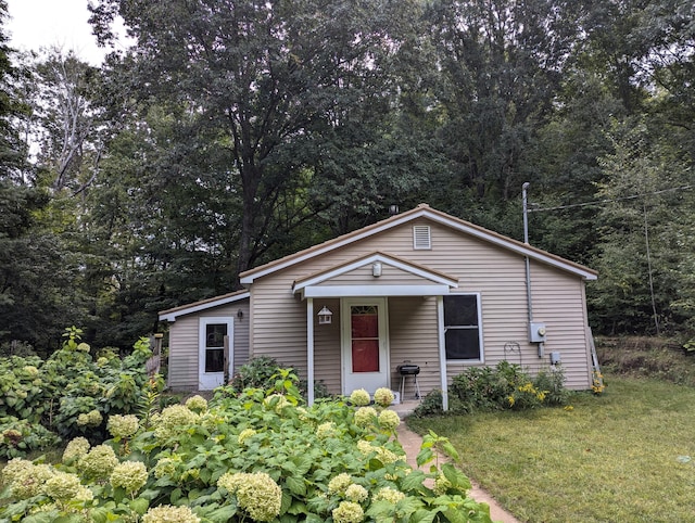 view of front facade with a front lawn and a view of trees