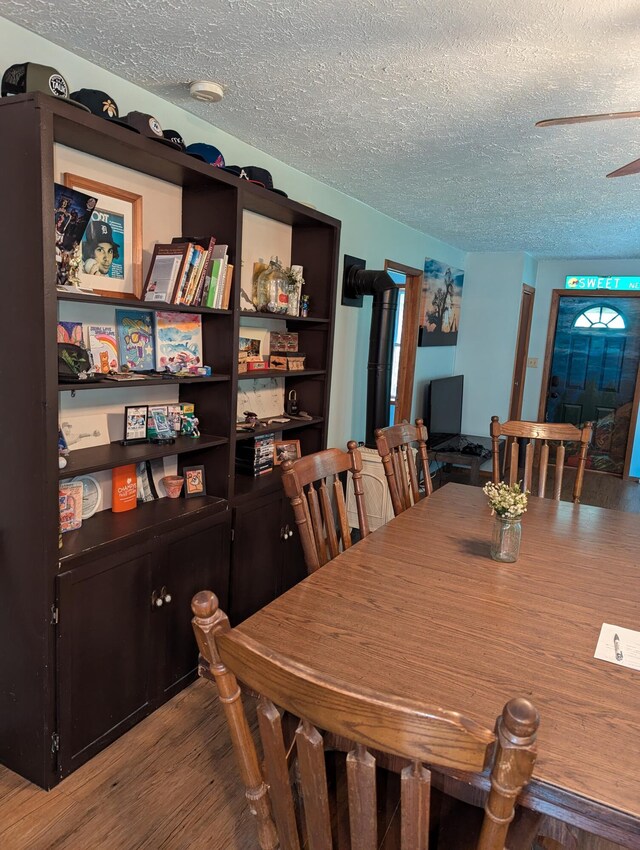 dining room featuring a textured ceiling, hardwood / wood-style floors, and ceiling fan