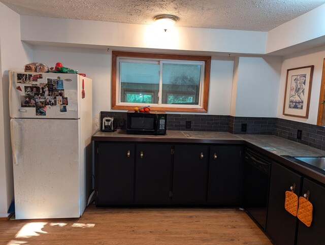 kitchen featuring light wood-type flooring, black appliances, decorative backsplash, and a textured ceiling