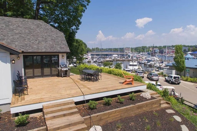 wooden deck featuring a water view and a grill