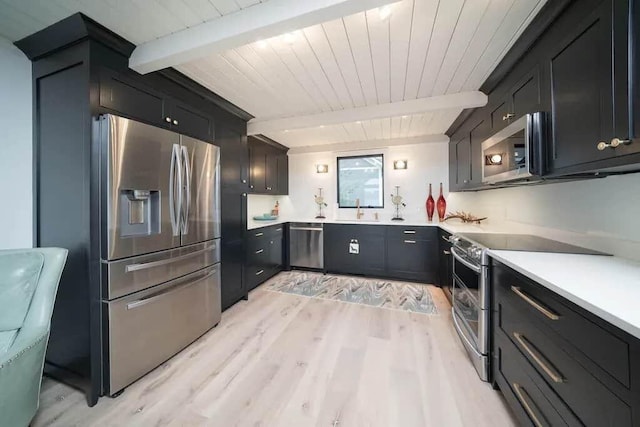 kitchen featuring stainless steel appliances, beamed ceiling, light wood-type flooring, and sink