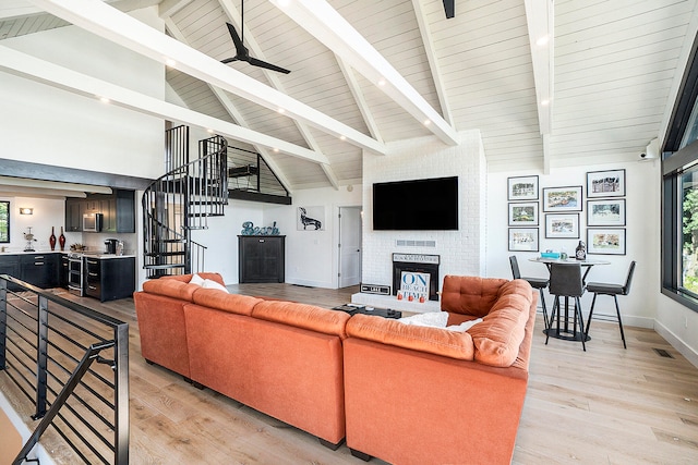 living room with light hardwood / wood-style floors, ceiling fan, high vaulted ceiling, and a brick fireplace