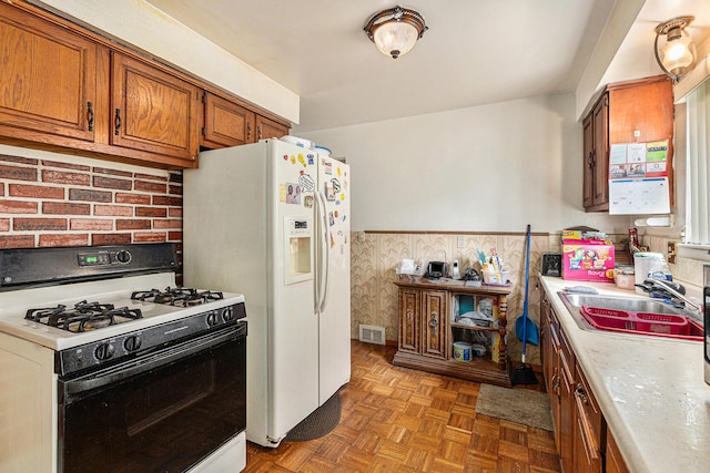 kitchen with white appliances, water heater, sink, and parquet floors