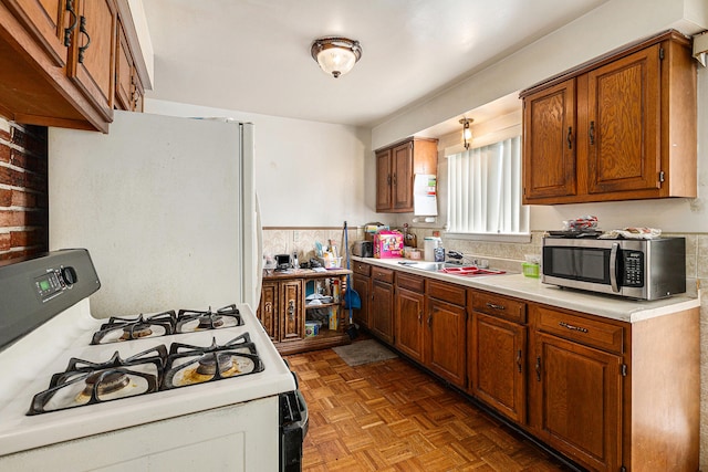 kitchen featuring white range with gas stovetop, sink, and light parquet flooring