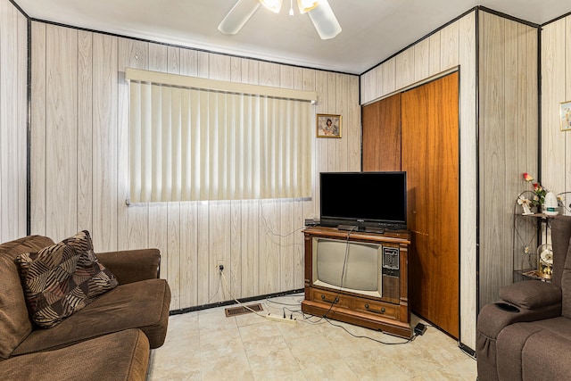 living room with ceiling fan and wooden walls