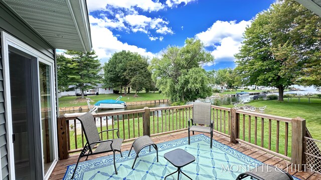 wooden terrace with a water view and a lawn