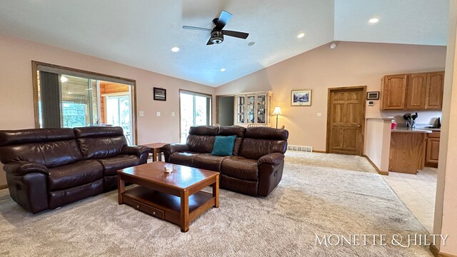 living room with high vaulted ceiling, ceiling fan, and light colored carpet