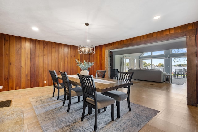 dining room featuring wooden walls and a chandelier