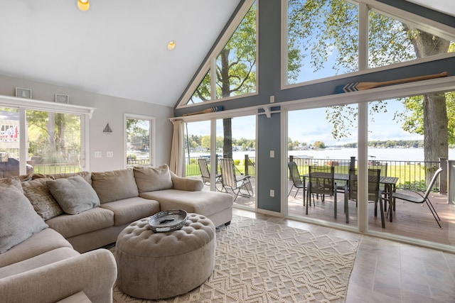 living room featuring a water view, high vaulted ceiling, light wood-type flooring, and a healthy amount of sunlight