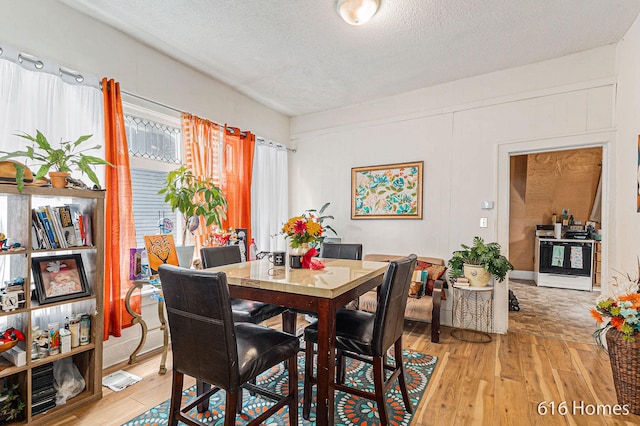 dining area featuring light wood-type flooring and a textured ceiling