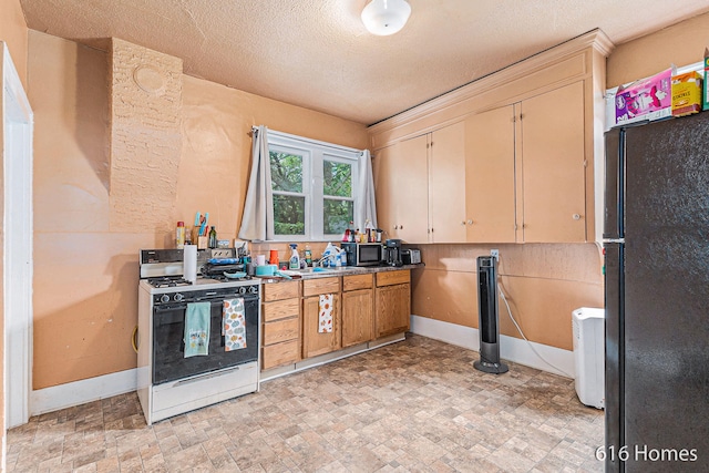 kitchen featuring a textured ceiling, white gas range oven, and black fridge