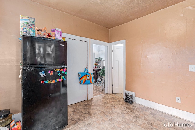 kitchen featuring a textured ceiling and black fridge