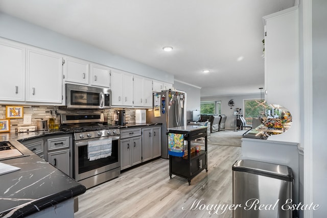 kitchen with gray cabinetry, appliances with stainless steel finishes, light hardwood / wood-style floors, tasteful backsplash, and white cabinetry