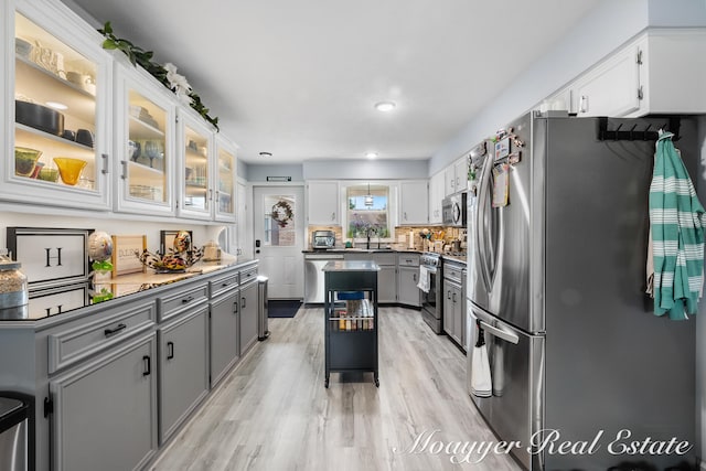 kitchen with gray cabinets, light wood-type flooring, stainless steel appliances, and white cabinets