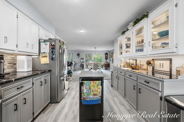 kitchen featuring gray cabinets, stainless steel fridge, pendant lighting, and light hardwood / wood-style floors