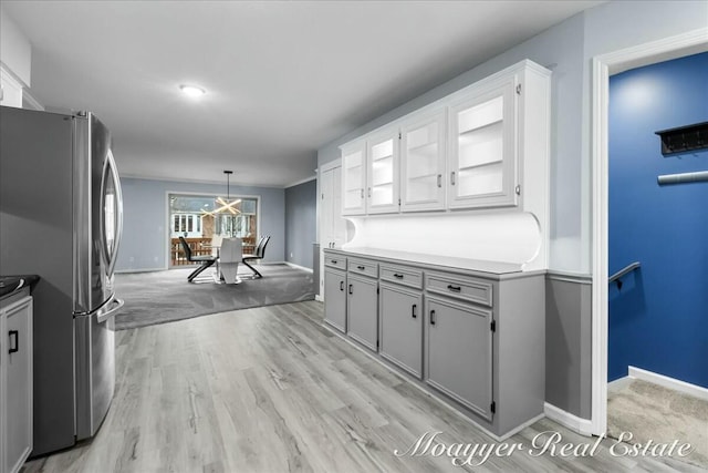 kitchen with light wood-style floors, gray cabinets, freestanding refrigerator, and baseboards