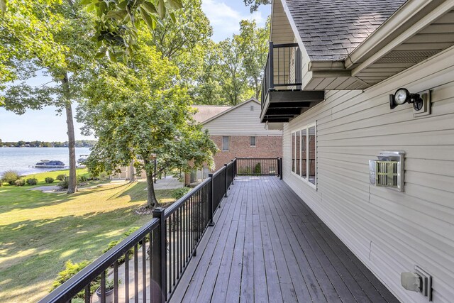 wooden terrace featuring a water view and a lawn