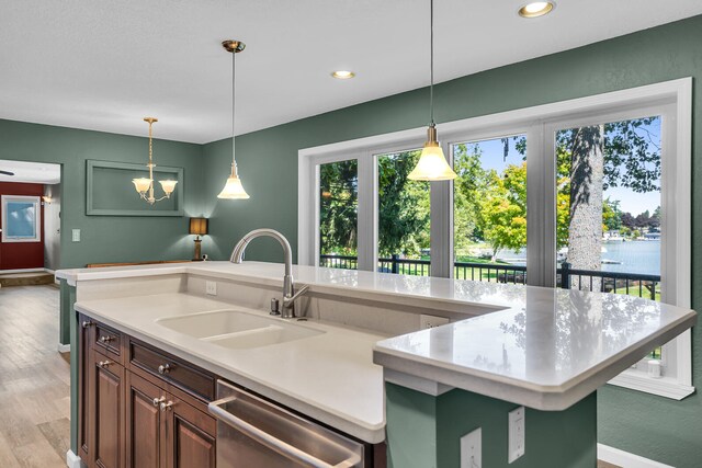 kitchen with dishwasher, sink, light hardwood / wood-style flooring, a kitchen island with sink, and a water view