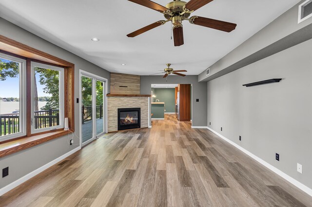 unfurnished living room featuring ceiling fan, light hardwood / wood-style floors, and a tiled fireplace