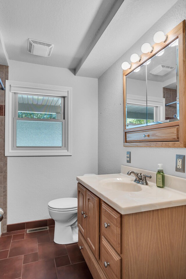 bathroom with a textured ceiling, vanity, toilet, and tile patterned floors