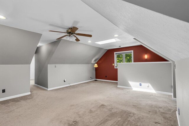 bonus room featuring light carpet, ceiling fan, and vaulted ceiling with skylight