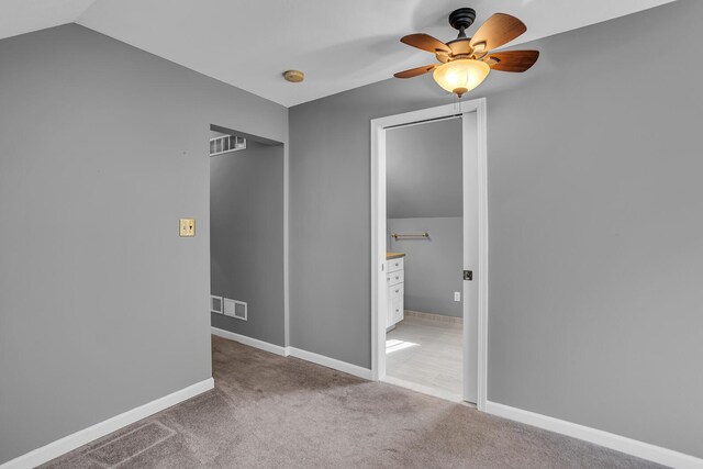 unfurnished bedroom featuring light colored carpet, vaulted ceiling, and ceiling fan