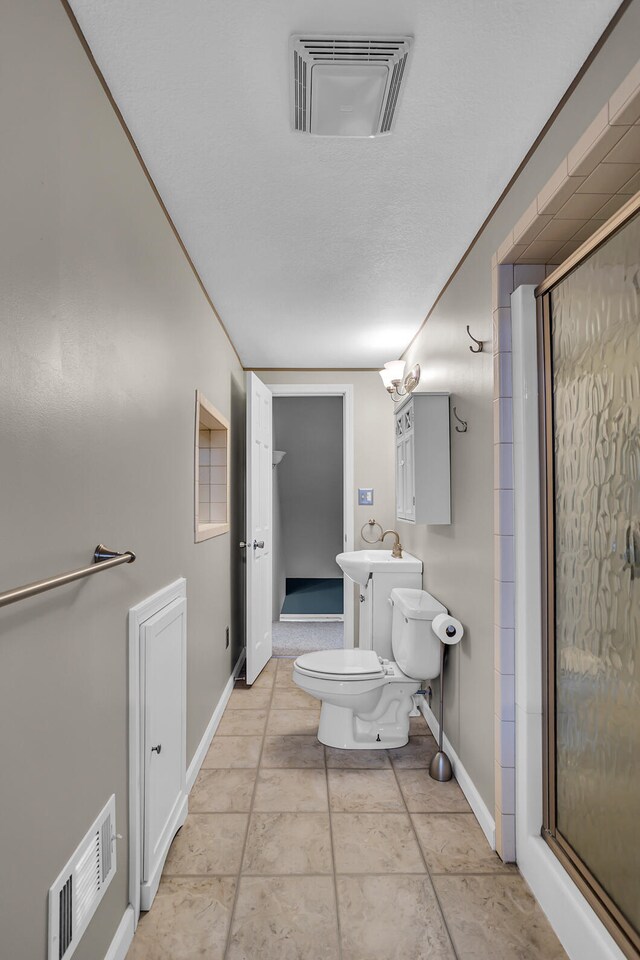 bathroom with sink, a shower with door, tile patterned flooring, and toilet