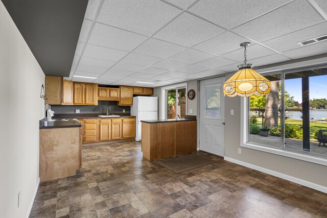 kitchen featuring decorative light fixtures, white fridge, a healthy amount of sunlight, and sink