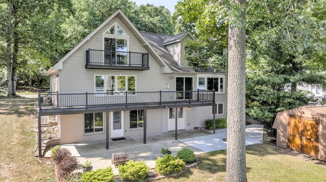 back of house featuring a balcony, a storage unit, a patio area, and a lawn