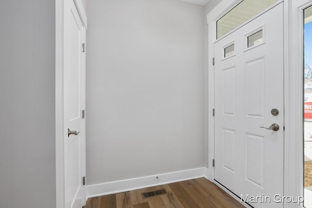 foyer entrance with dark wood-type flooring, visible vents, and baseboards