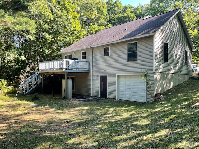 rear view of property featuring a garage, a lawn, and a deck