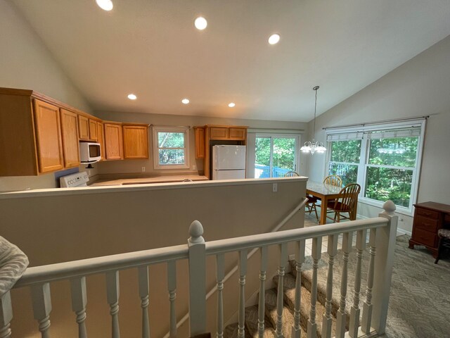 kitchen with lofted ceiling, hanging light fixtures, a notable chandelier, carpet, and white appliances