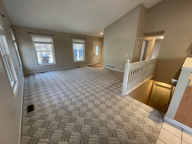 carpeted foyer with high vaulted ceiling