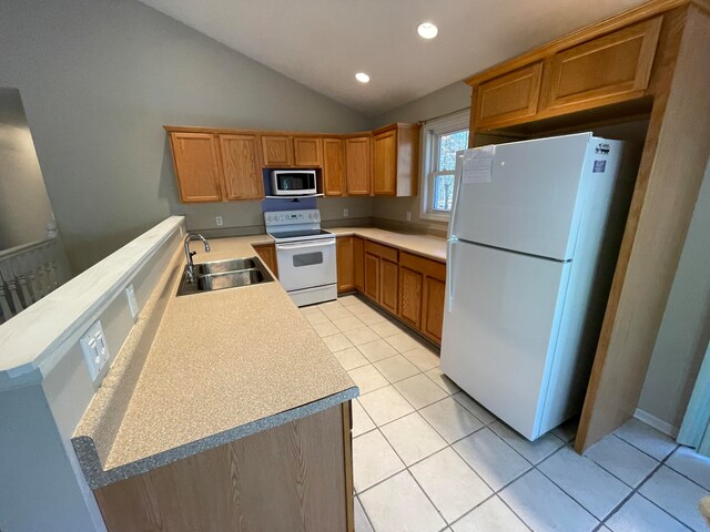 kitchen with sink, white appliances, vaulted ceiling, and light tile patterned floors