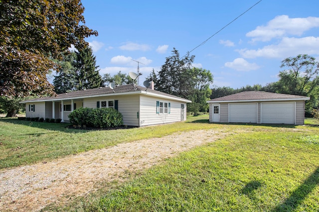 rear view of house featuring a yard, a garage, and an outbuilding