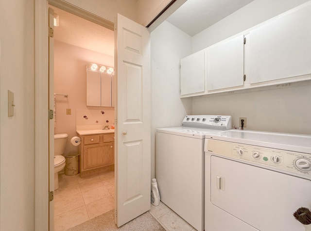 washroom featuring washer and clothes dryer, light tile patterned flooring, and cabinets