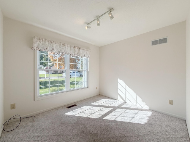 carpeted spare room featuring rail lighting