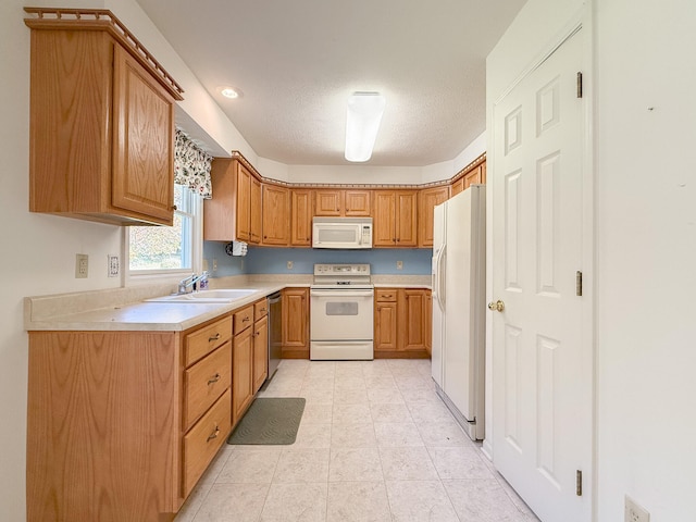 kitchen with a textured ceiling, sink, and white appliances