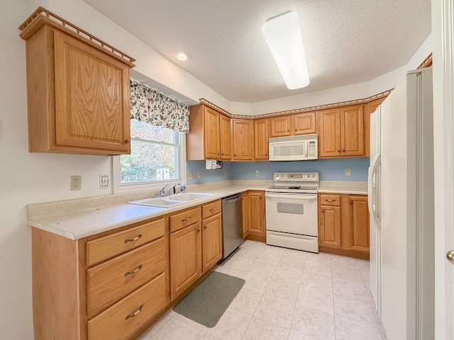 kitchen with a textured ceiling, white appliances, and sink