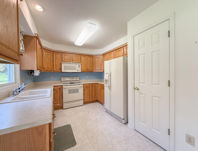 kitchen with a textured ceiling, sink, and white appliances