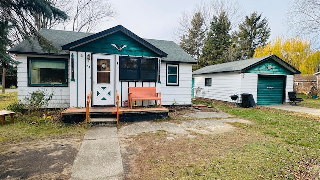 bungalow featuring a garage, an outbuilding, and a front yard